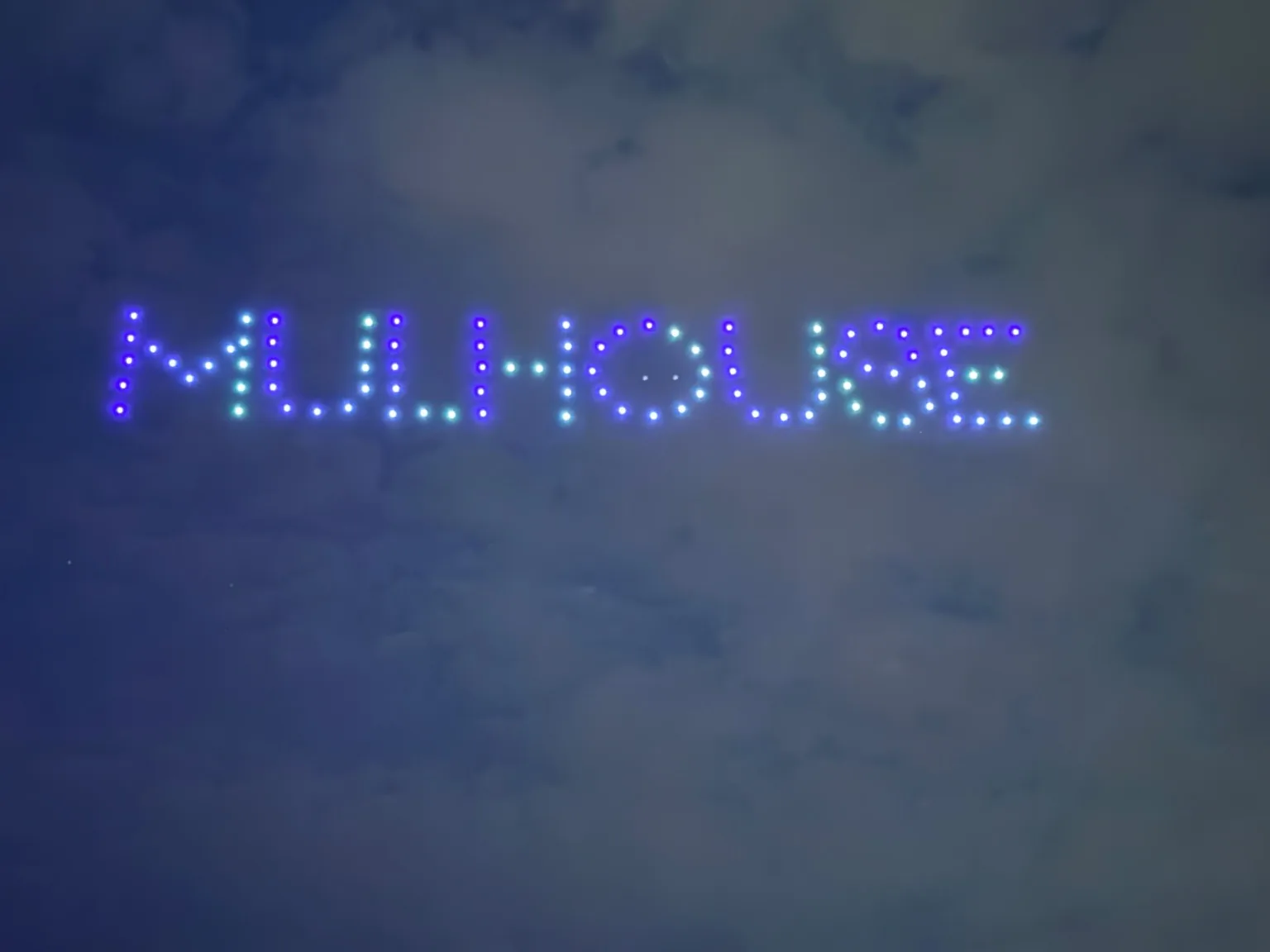 Message écrit en lettres lumineuses dans le ciel par une flotte de drones